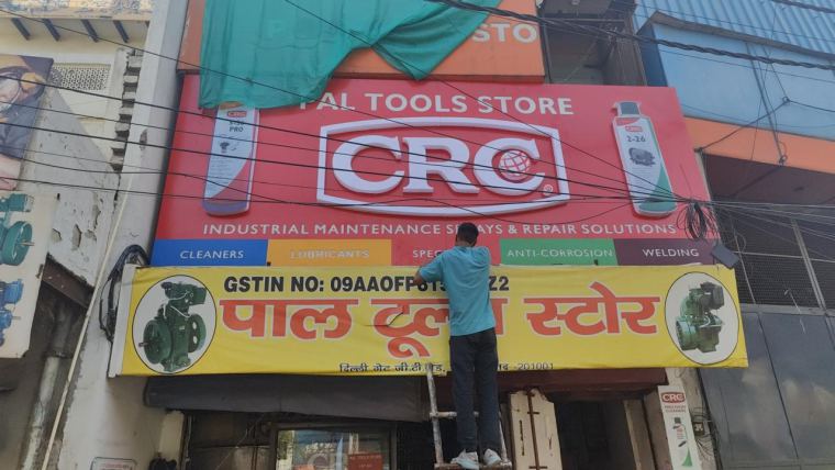 Technician installing a framed flex banner board on a shop front