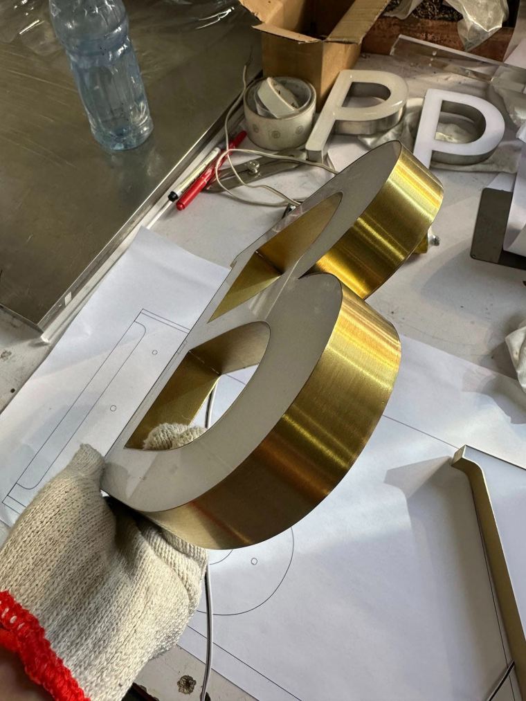 Gold-finish 3D letters being finished by hand in the CADMAP workshop