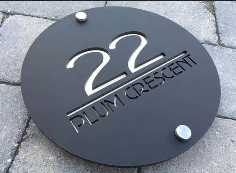 Round black acrylic house name plate with laser-cut lettering and steel stand-offs